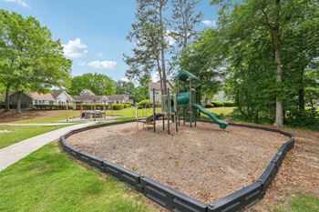 A playground with a green slide and a black fence.